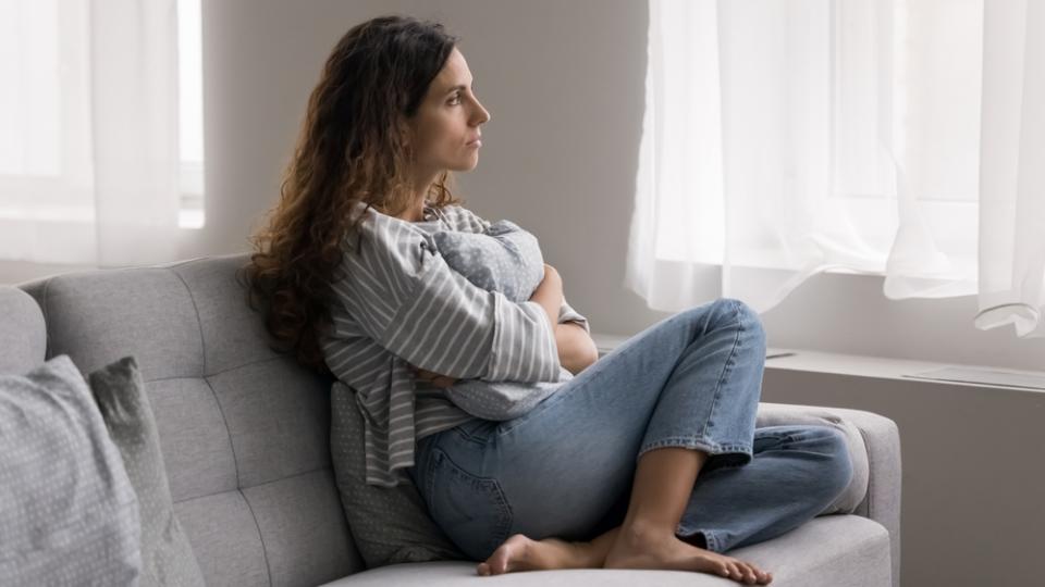 Frau mit Anzeichen einer Depression blickt aus dem Fenster