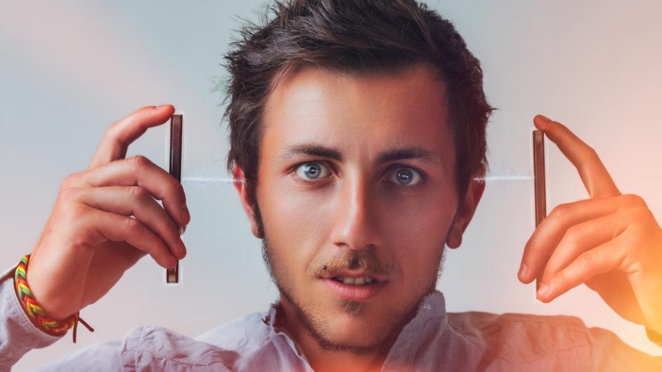 Mann testet die Wirkung von Frequenzen mit zwei Stäben